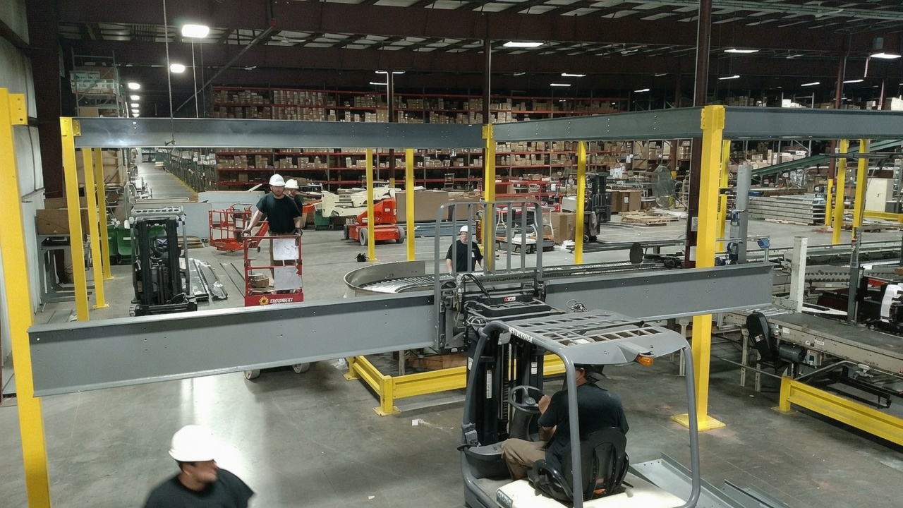 Worker performing maintenance on an overhead conveyor from a scissor lift